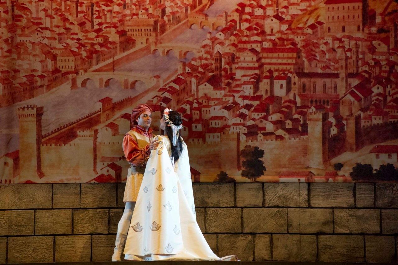 Scena di Gianni Schicchi: due interpreti in costume rinascimentale davanti a un fondale dipinto con la veduta di Firenze